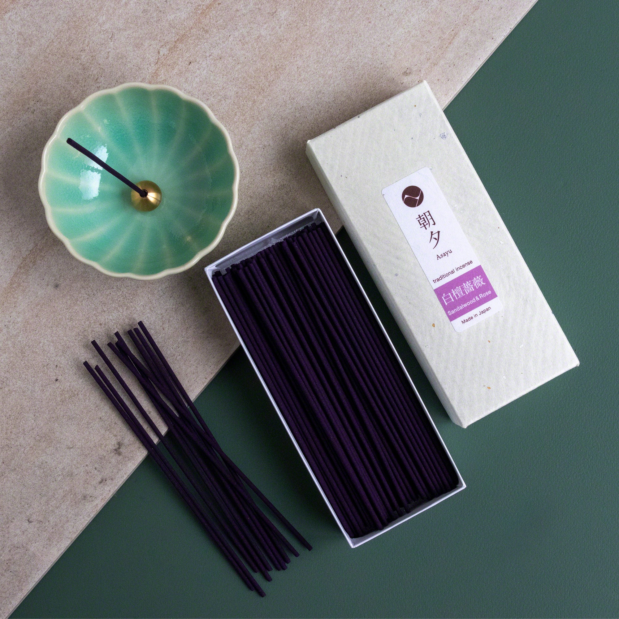 Open box of Asayu Japan Sandalwood and Rose Traditional Incense Sticks next to an Asayu Japan Turquoise Mini Lotus Flower Incense Holder.