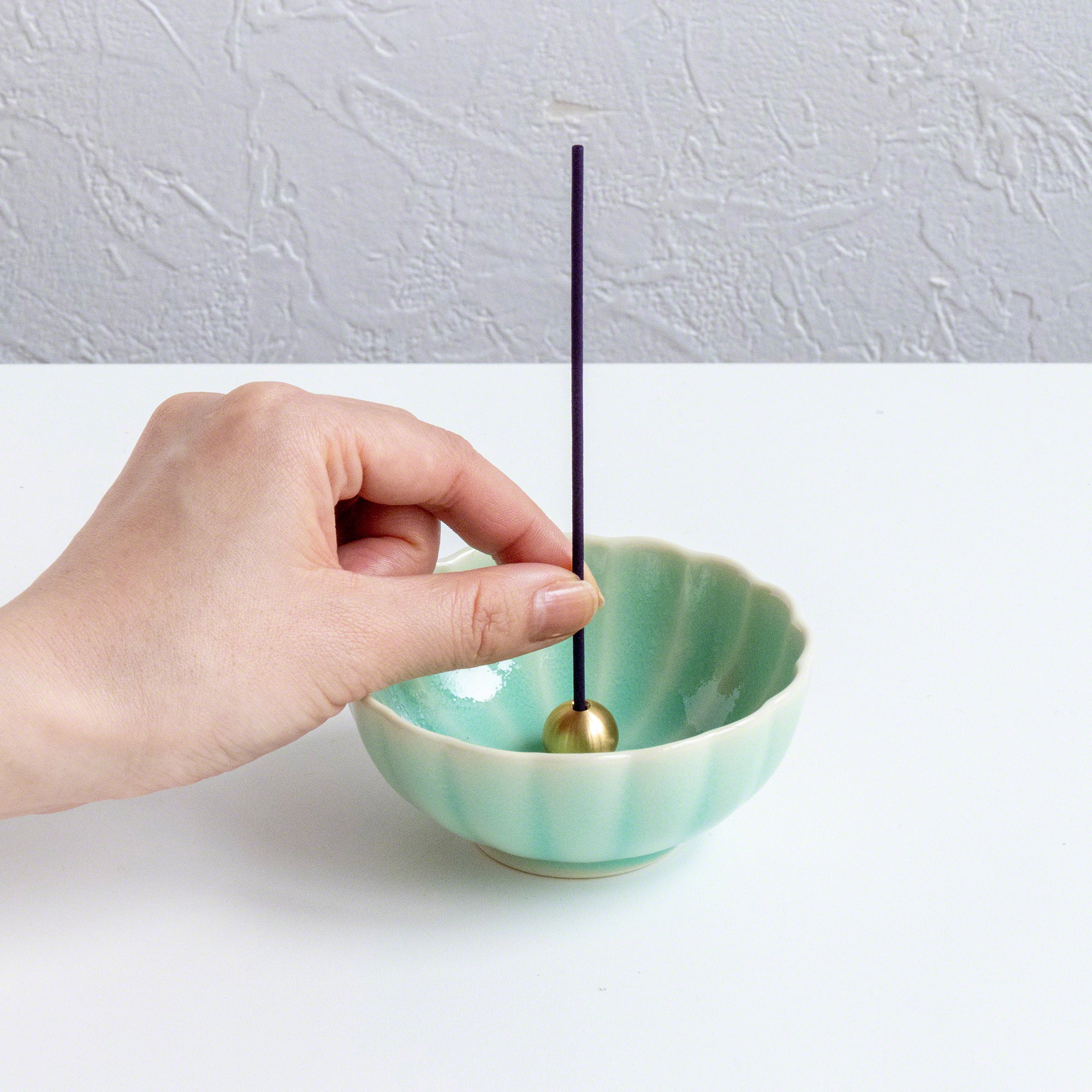 Put the sandalwood and rose incense stick in an incense stand over an incense plate or similar surface