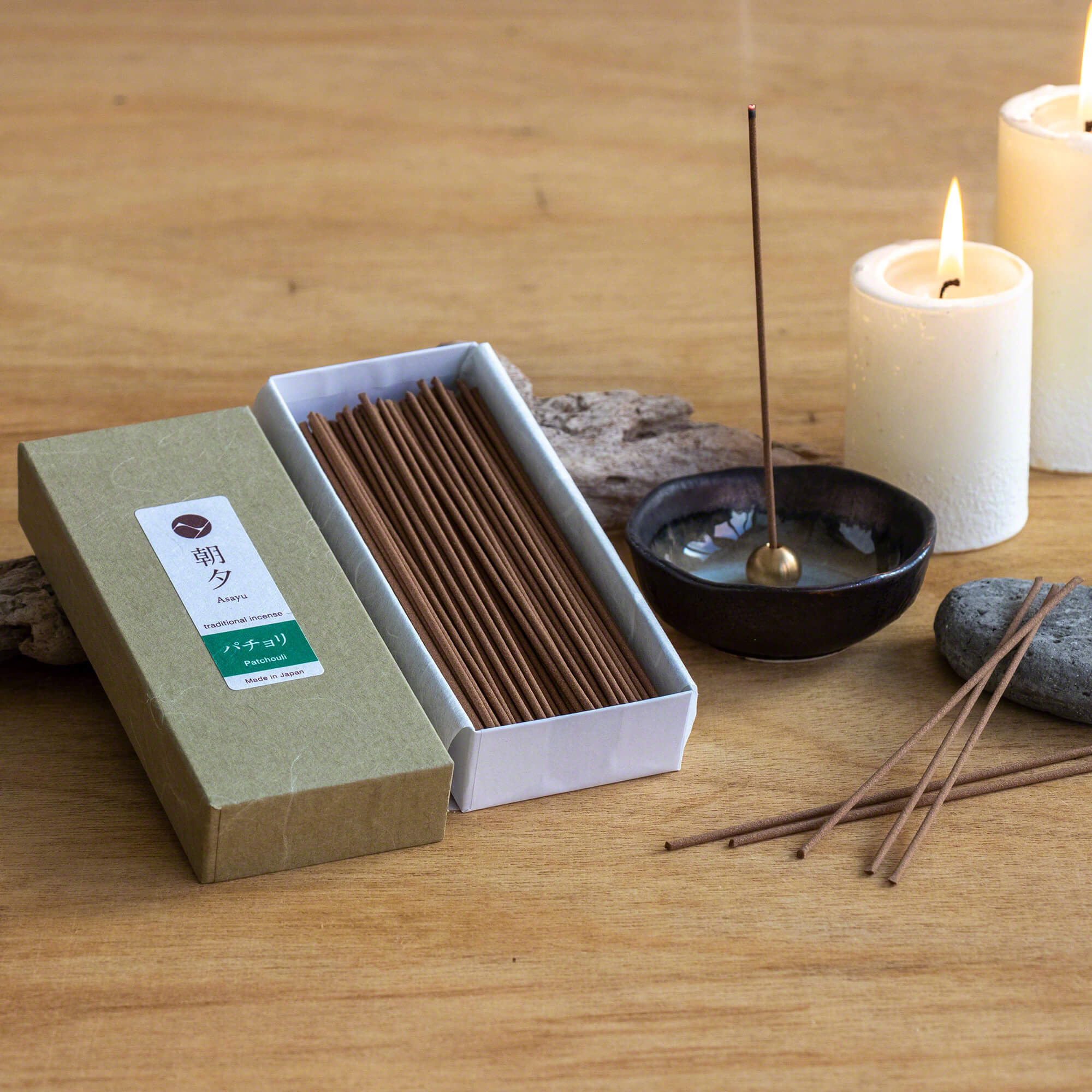 box of patchouli incense next to incense holder and candles