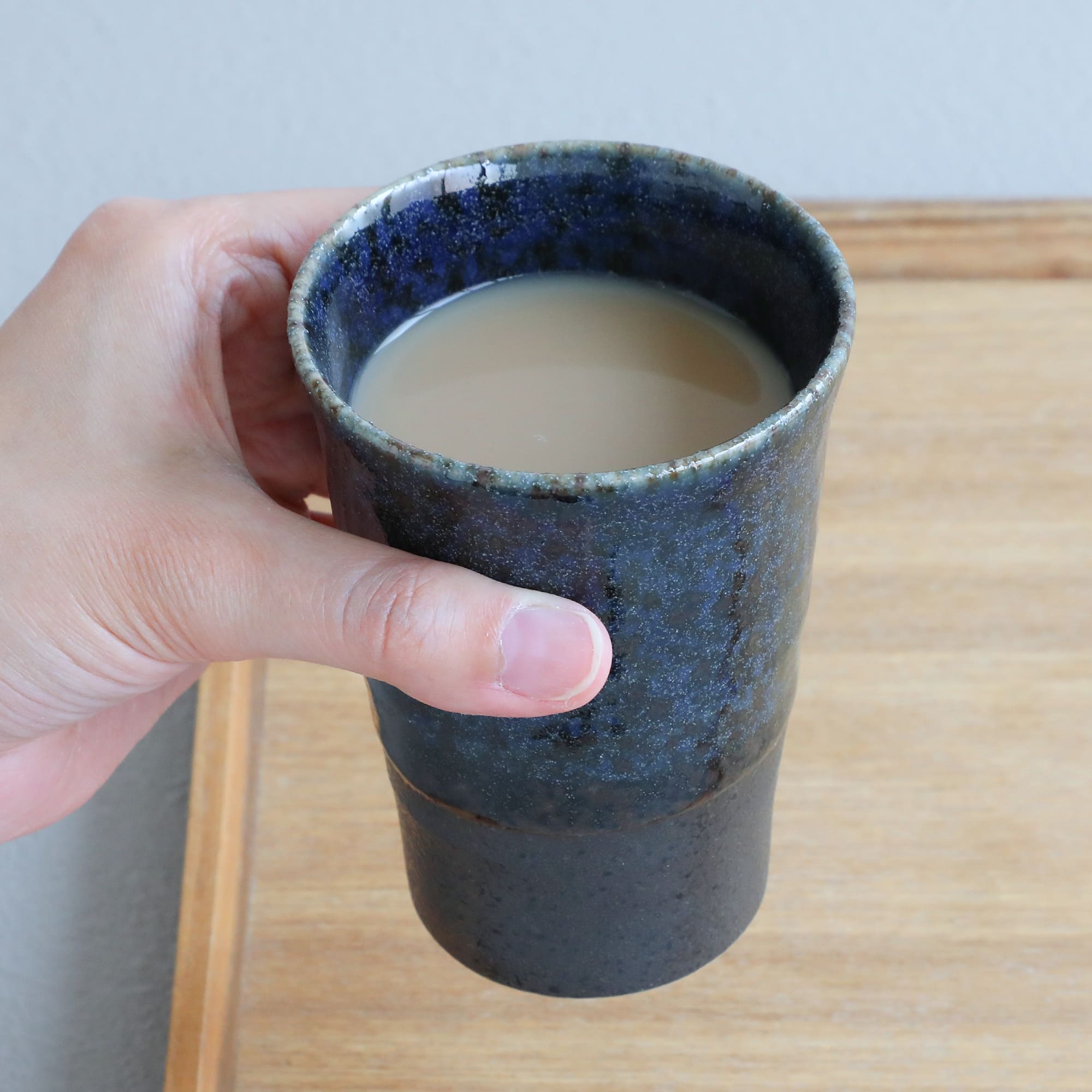 hand holding a Blue Tea cup with tea inside