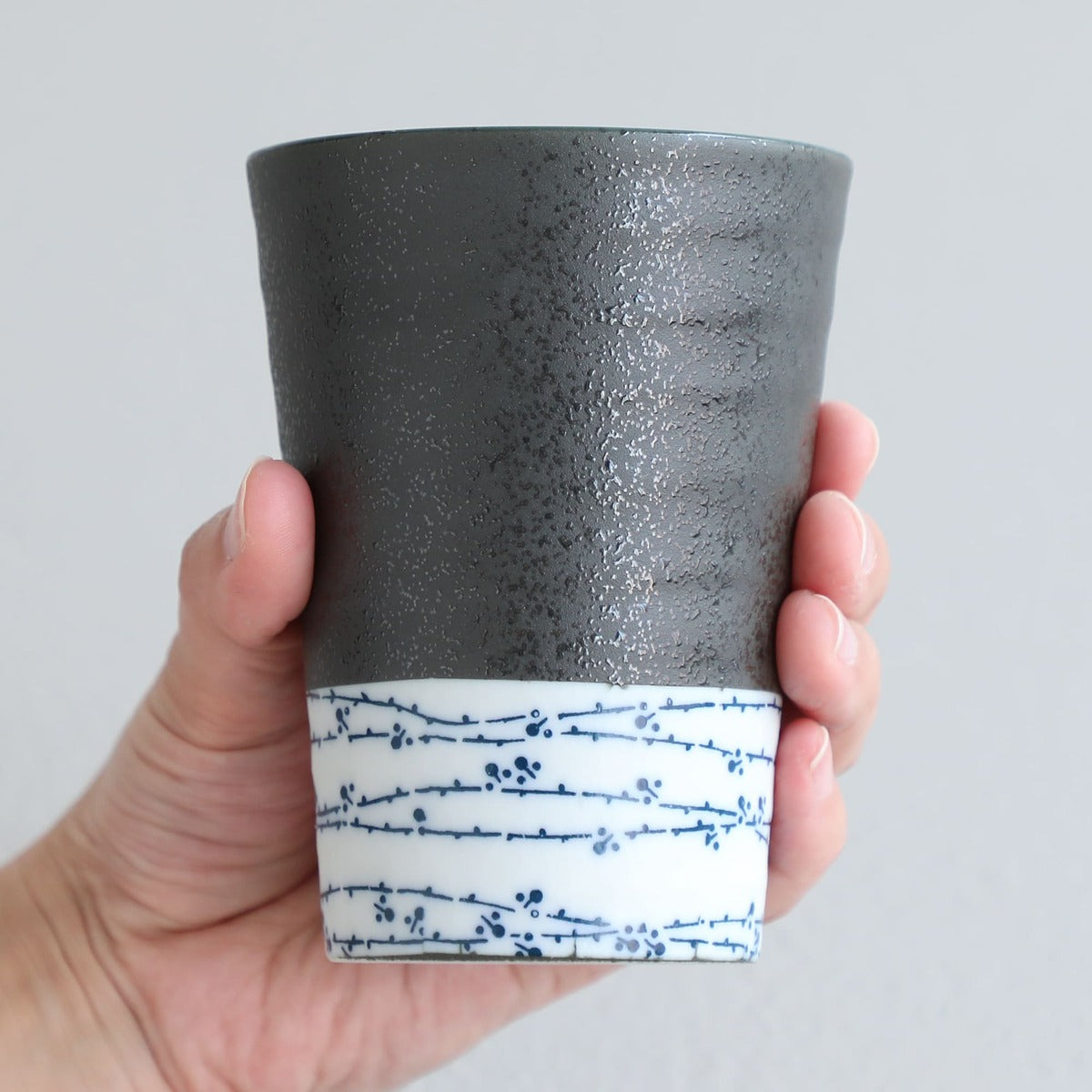 hand holding grey and white tea cup