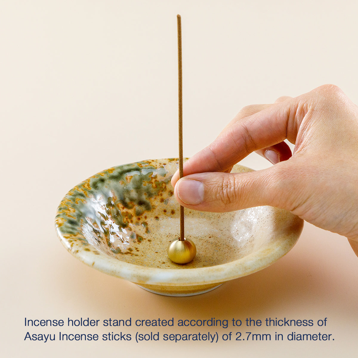 hand placing ncense in orange ceramic holder