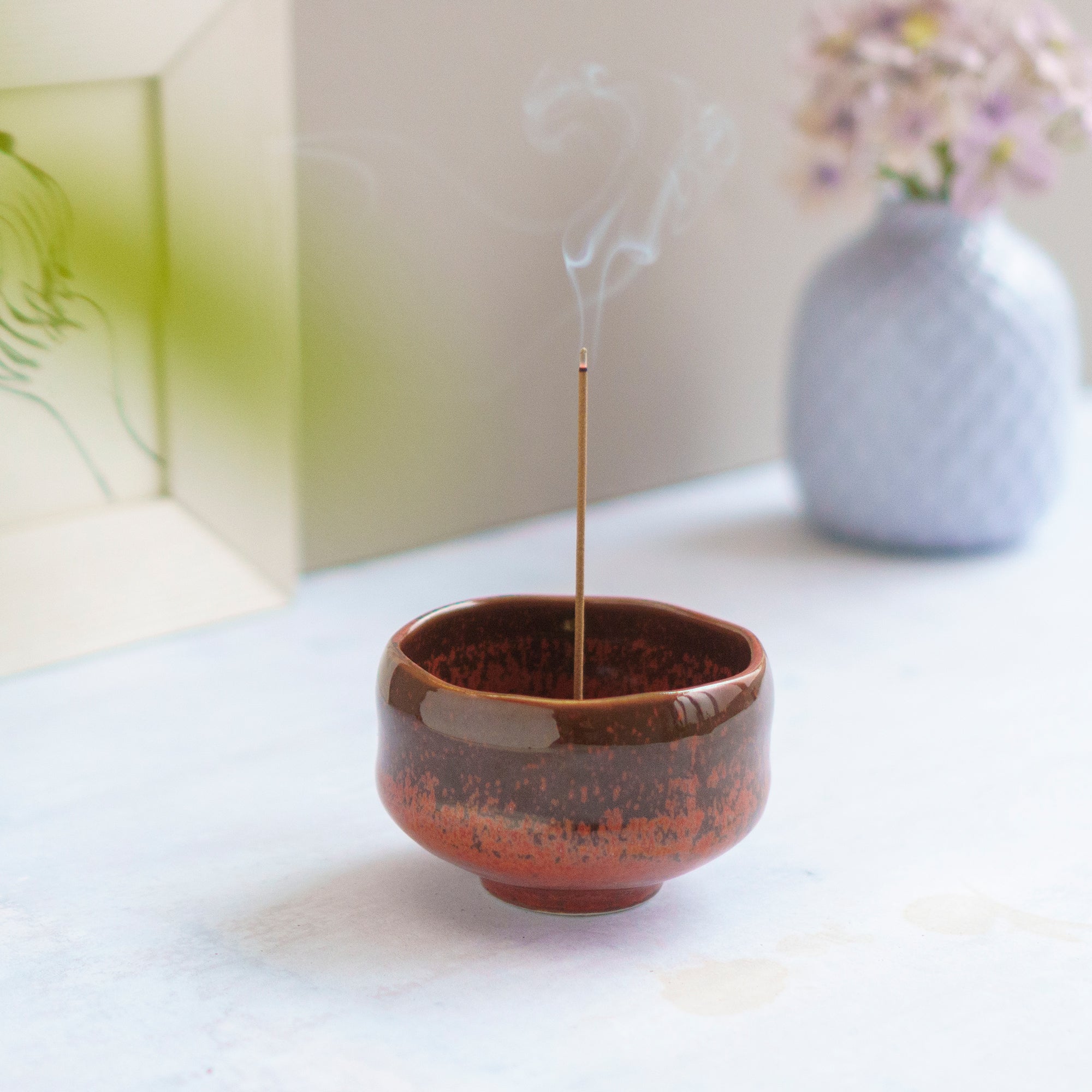 incense burning in an orange ceramic incense holder