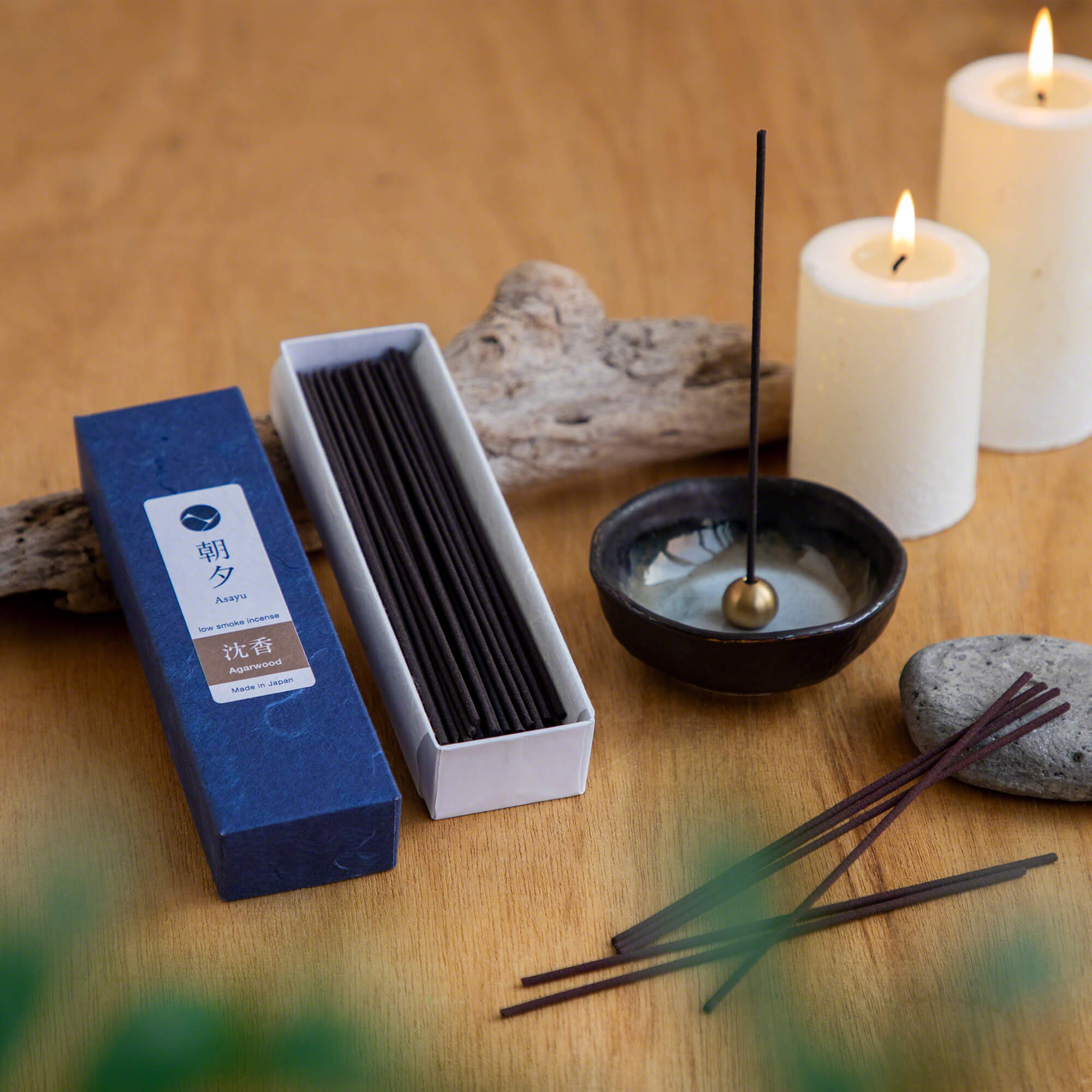 open box of agarwood incense next to an incense holder and candle