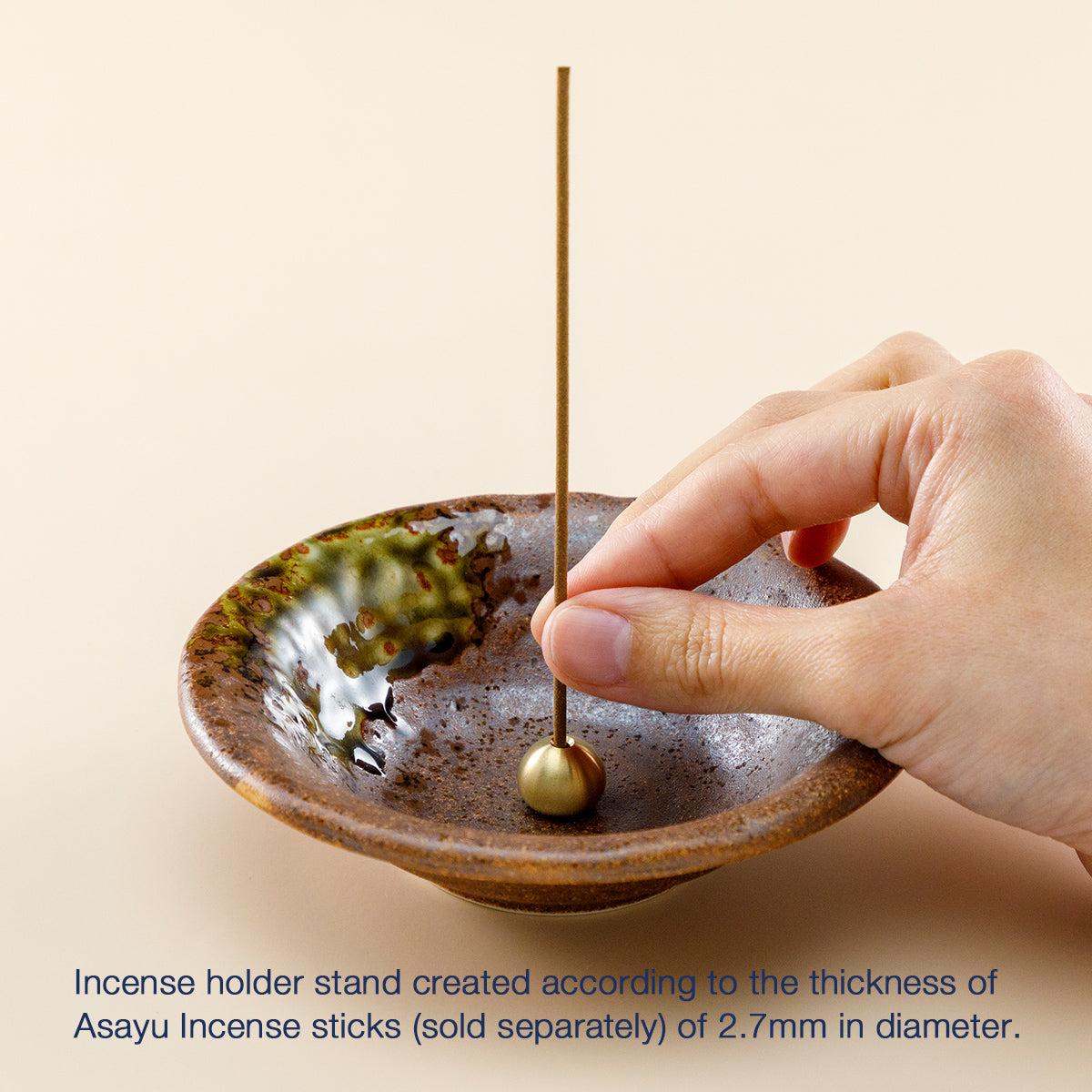 hand placing an incense stick in the incnese holder