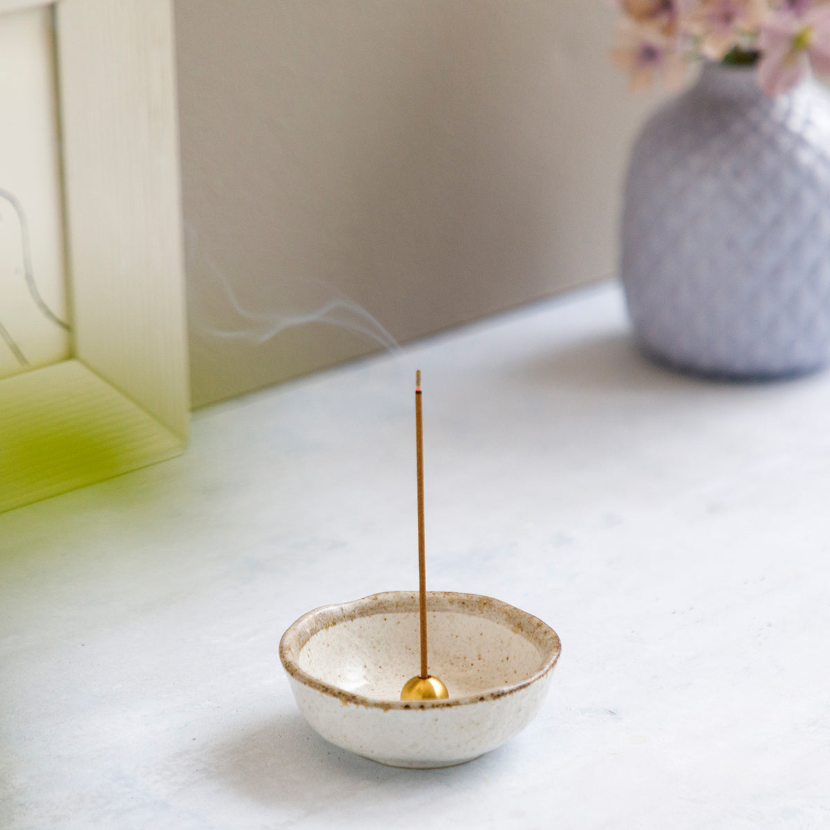 incense burning in brass holder placed within white ceramic holder