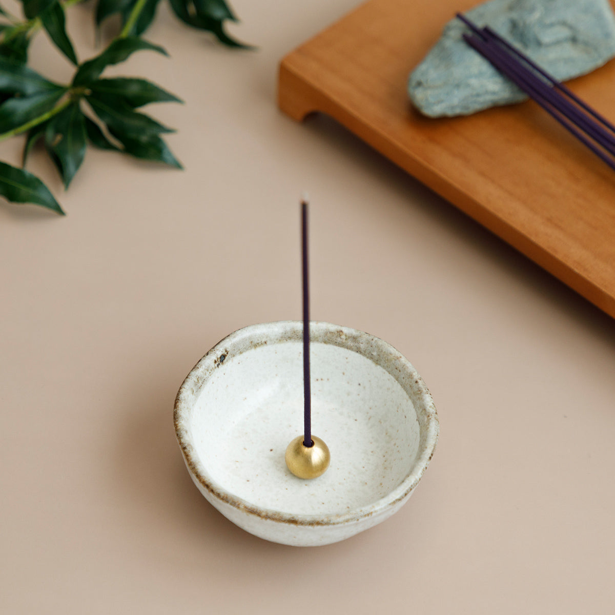 incense place in brass holder within white ceramic incense holder