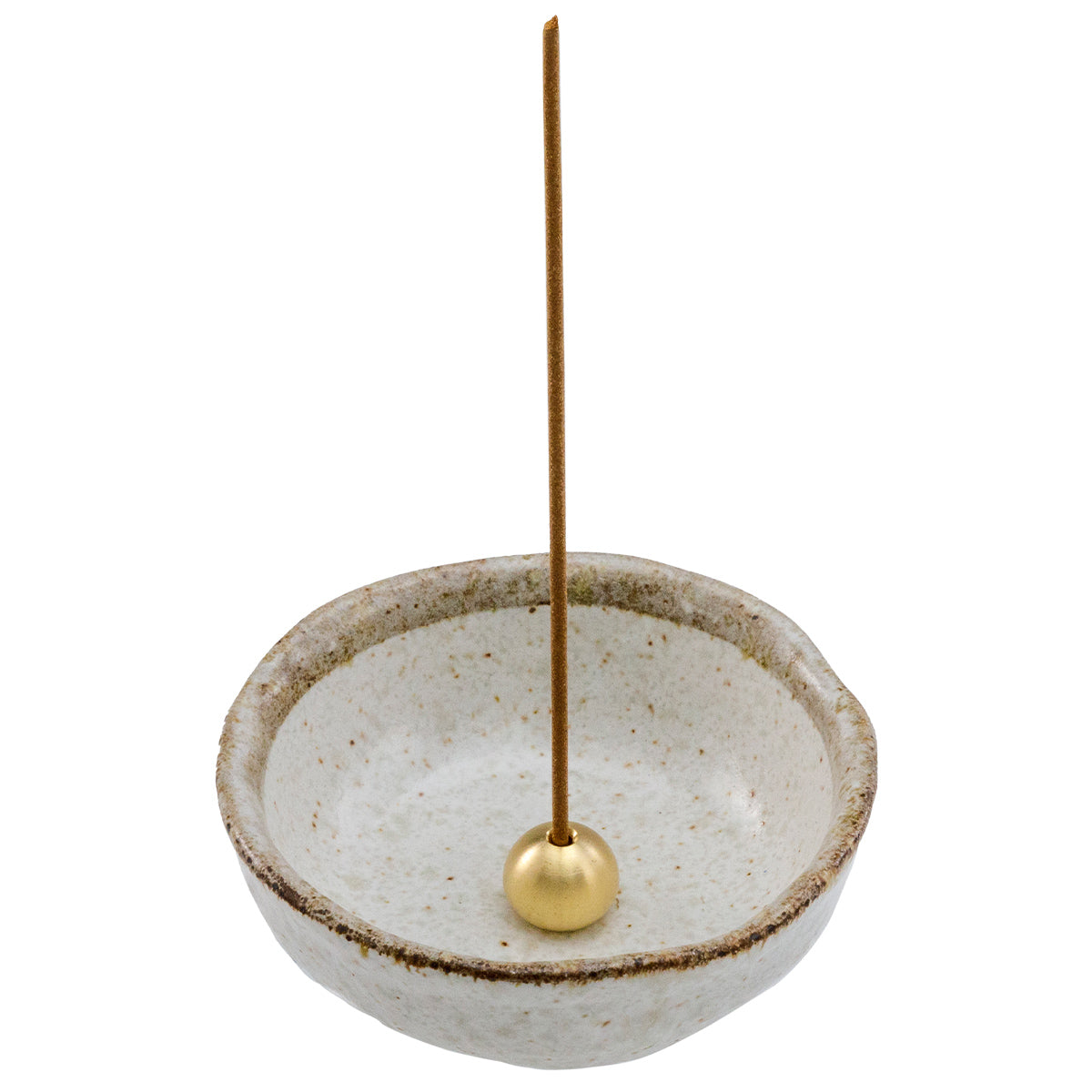 incense stick in brass holder within white ceramic holder
