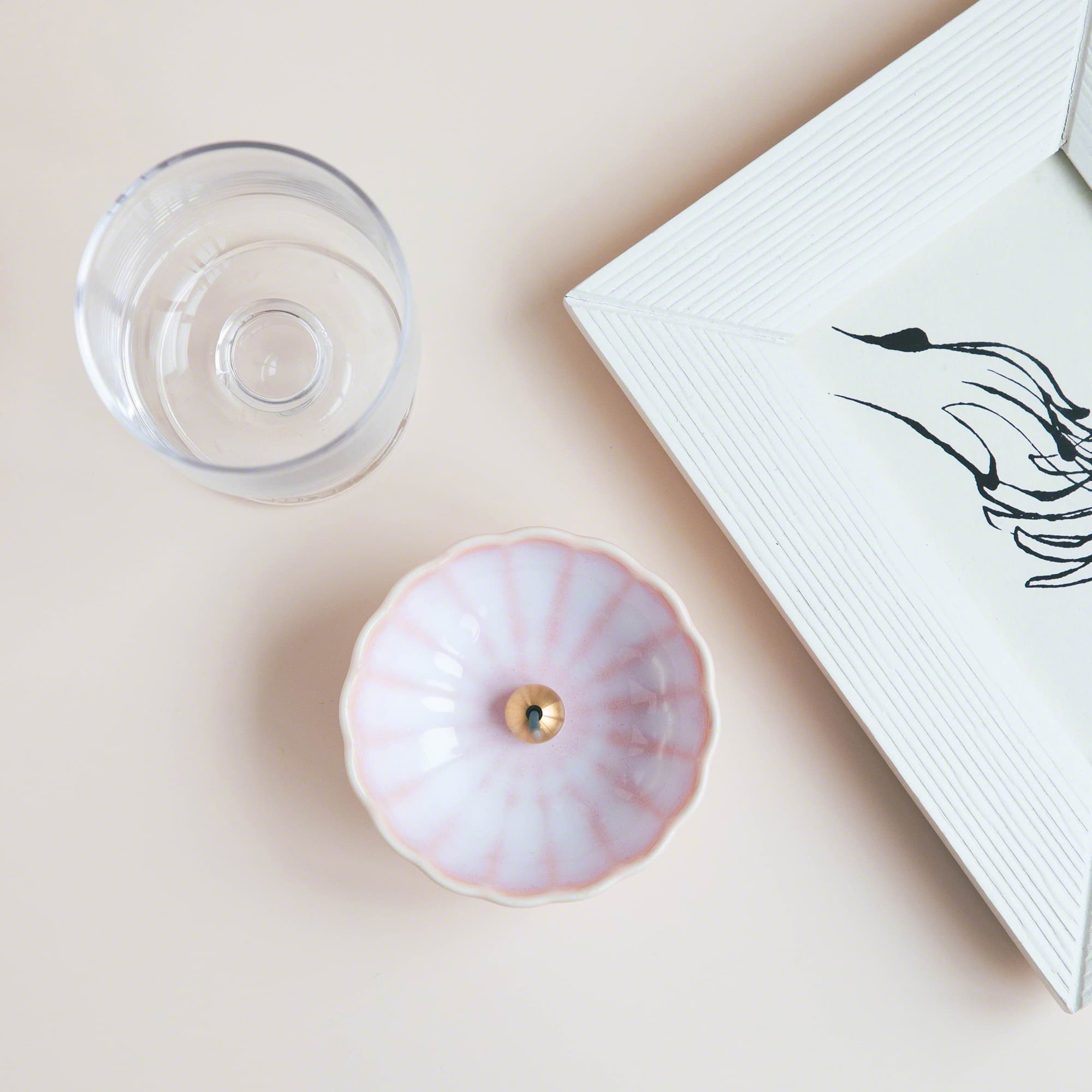 Cherry Blossom Pink Mini Lotus Flower Incense Holder on a table next to a glass of water.