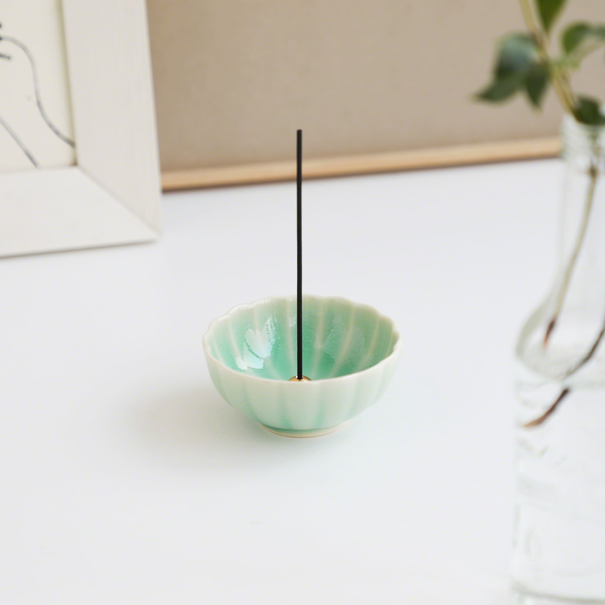 Turquoise Mini Lotus Incense Holder by Asayu Japan with a stick in a desk.
