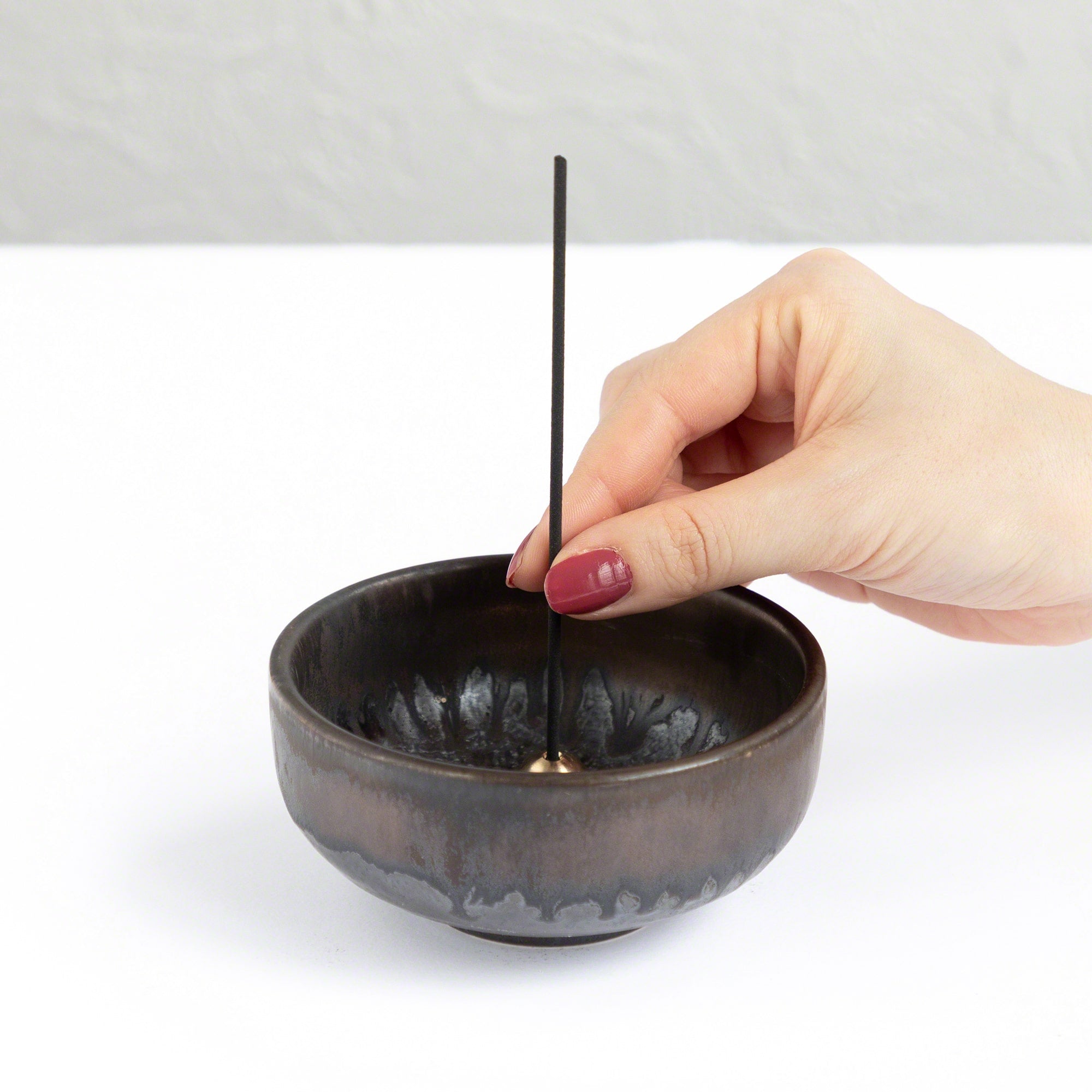 Put the plum blossom incense stick in an incense stand over an incense plate or similar surface