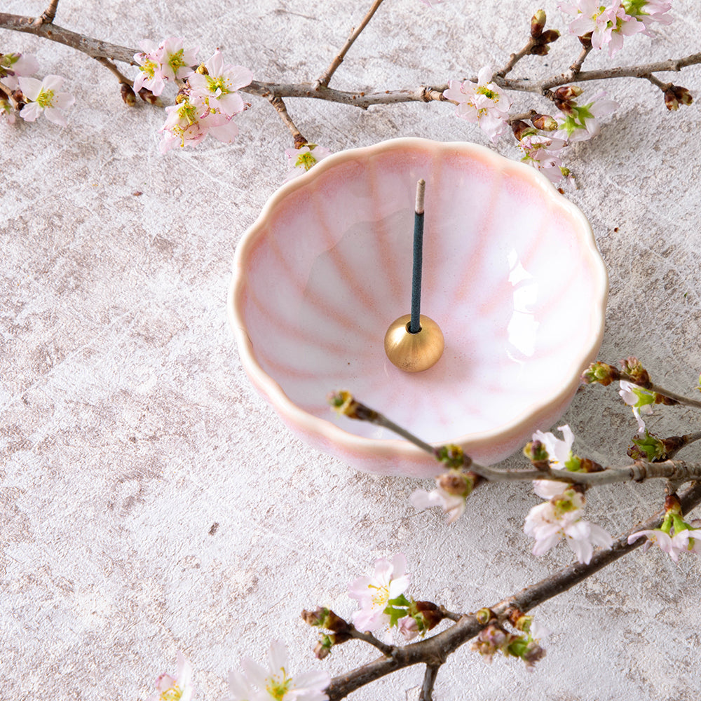 Asayu Japan Cherry Blossom Pink Mini Lotus Incense Holder with a burning incense stick on it surrounded by blooming sakura branches.