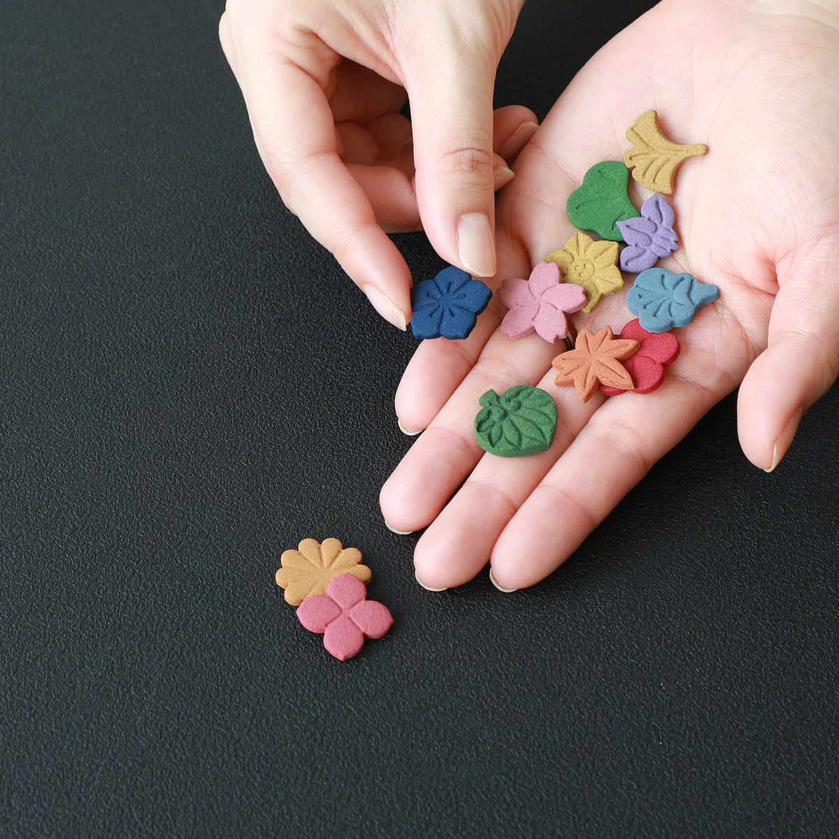 Colourful 12 pieces of pressed incense by Asayu Japan spread out on the hand of a person