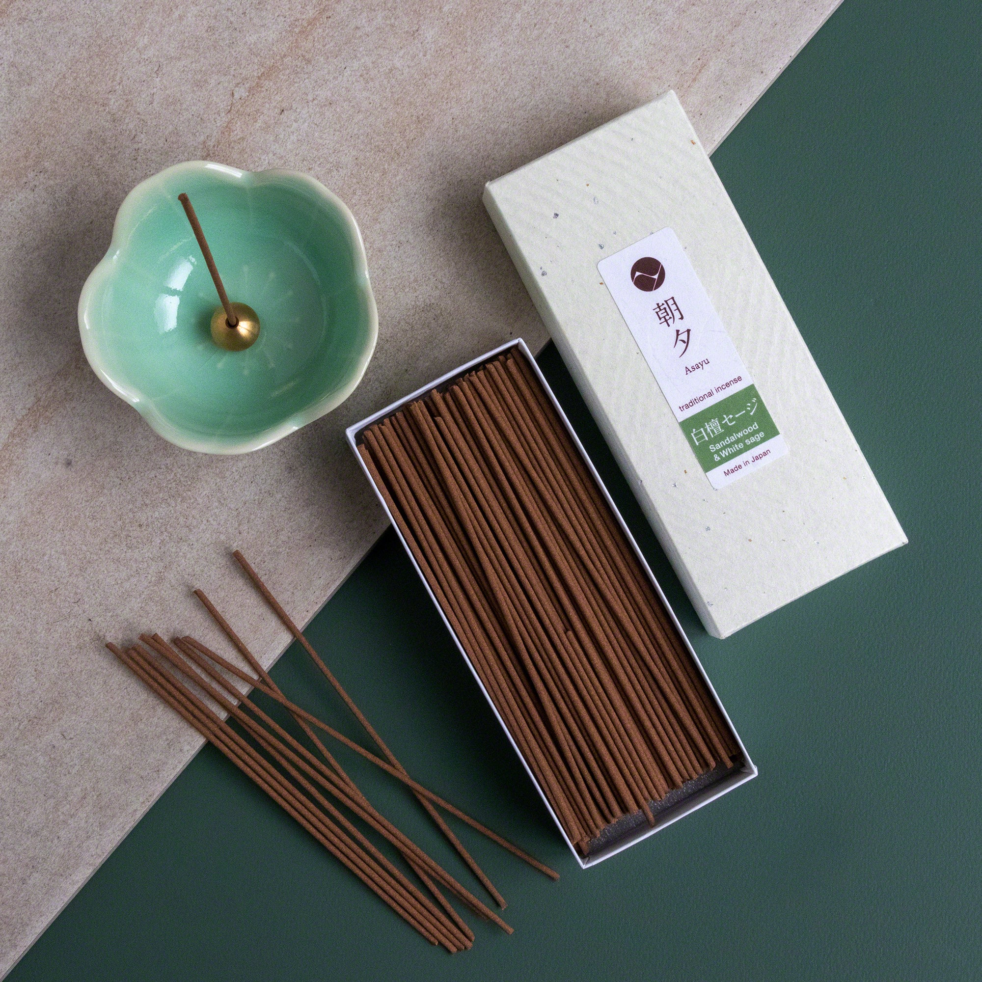 Open box of Asayu Japan White Sage and Sandalwood Traditional Incense Sticks next to an Asayu Japan Turquoise Mini Sakura Flower Incense Holder.