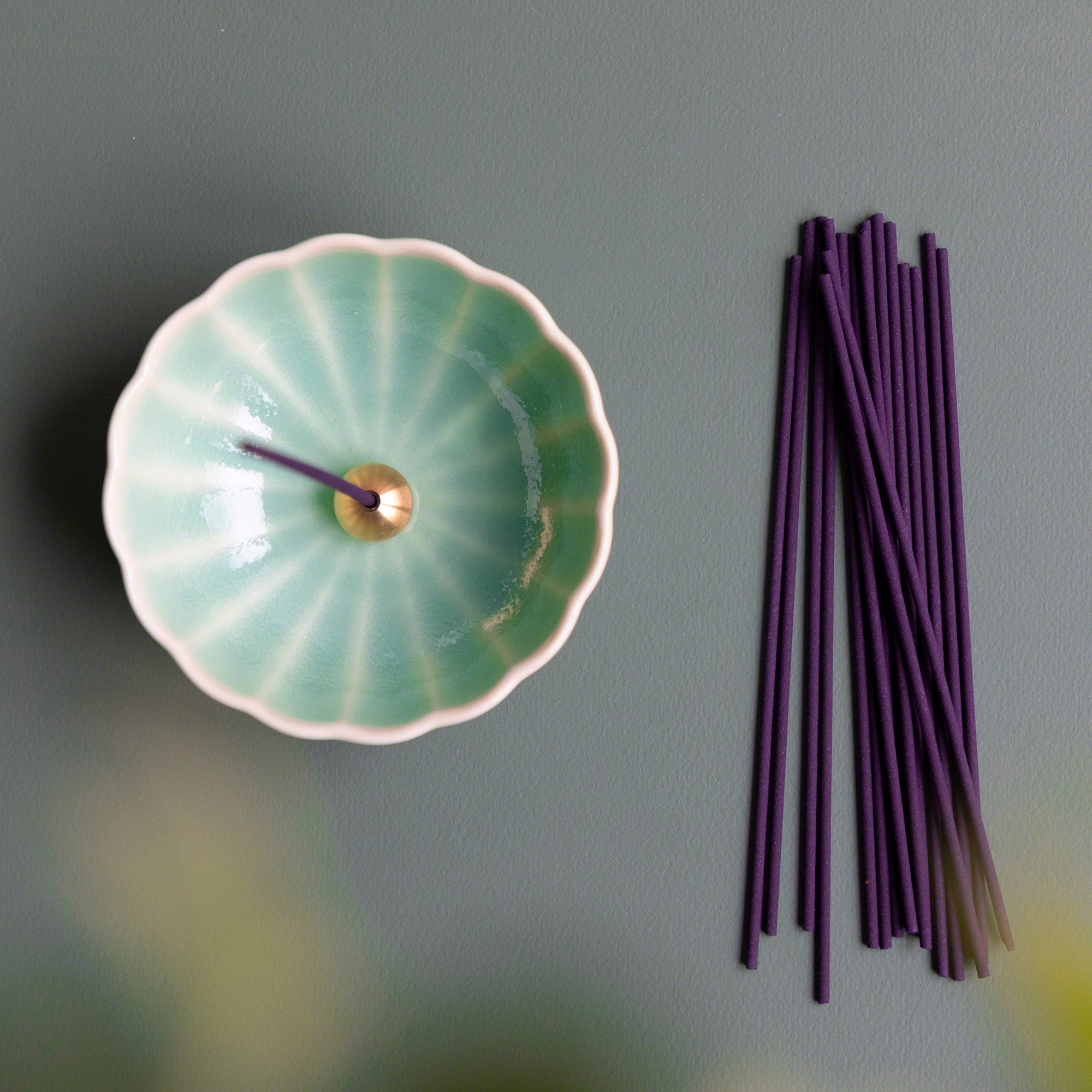 Dark pink sandalwood and rose blend traditional smoke incense sticks by Asayu Japan next to a turquoise mini lotus flower incense holder.