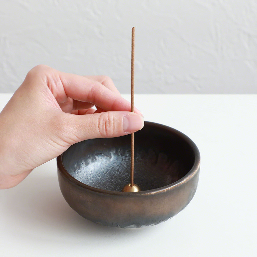 Put the patchouli incense stick in an incense stand over an incense plate or similar surface