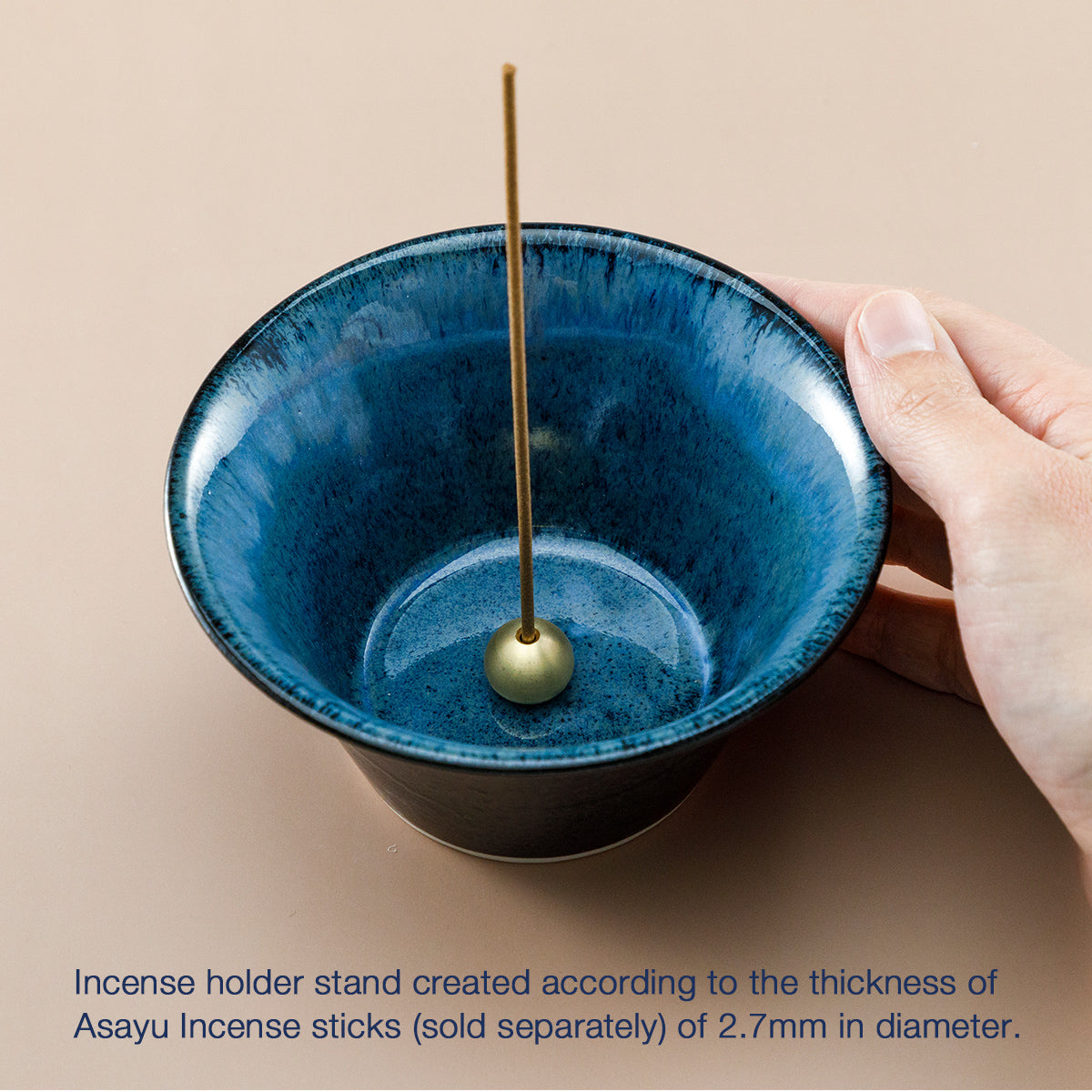hand holding blue and black incense holder