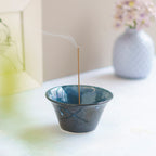 incense burning in cone shaped blue and black incense holder