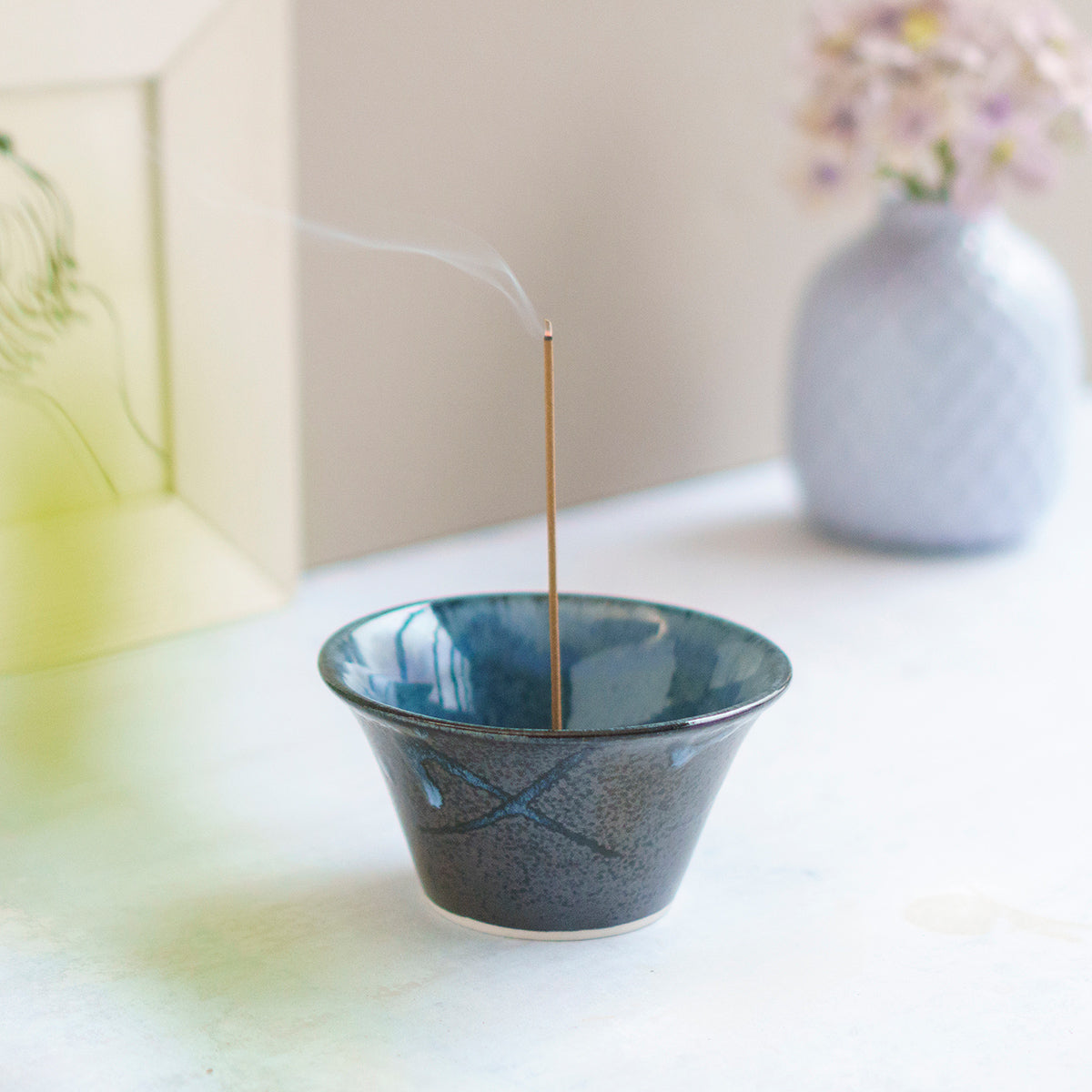 incense burning in cone shaped blue and black incense holder