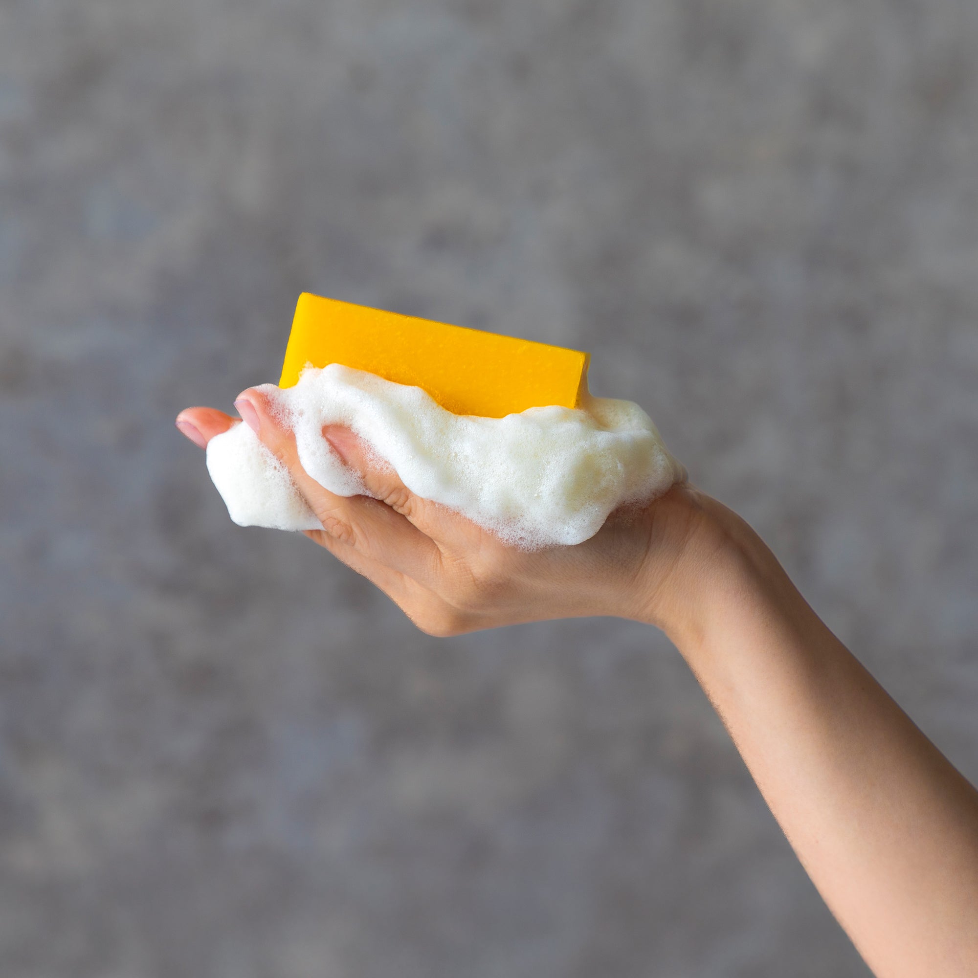 Hand Holding a Persimmon soap on a gray background