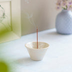 cone shaped white incense holder with burning incense
