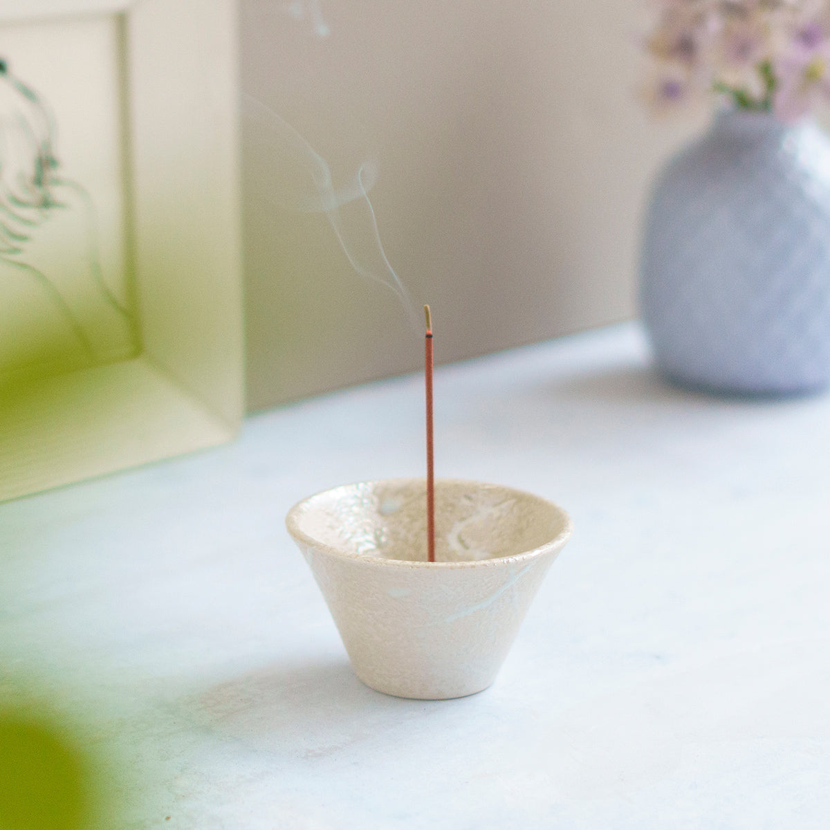 cone shaped white incense holder with burning incense