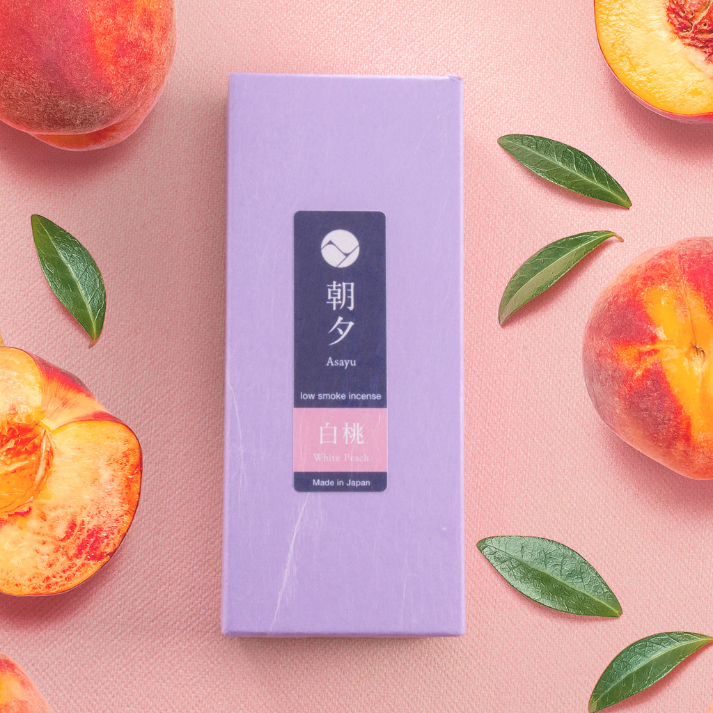 Peach incense sticks box next to peaches