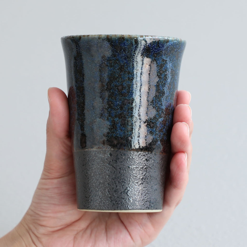 hand holding a blue tea cup