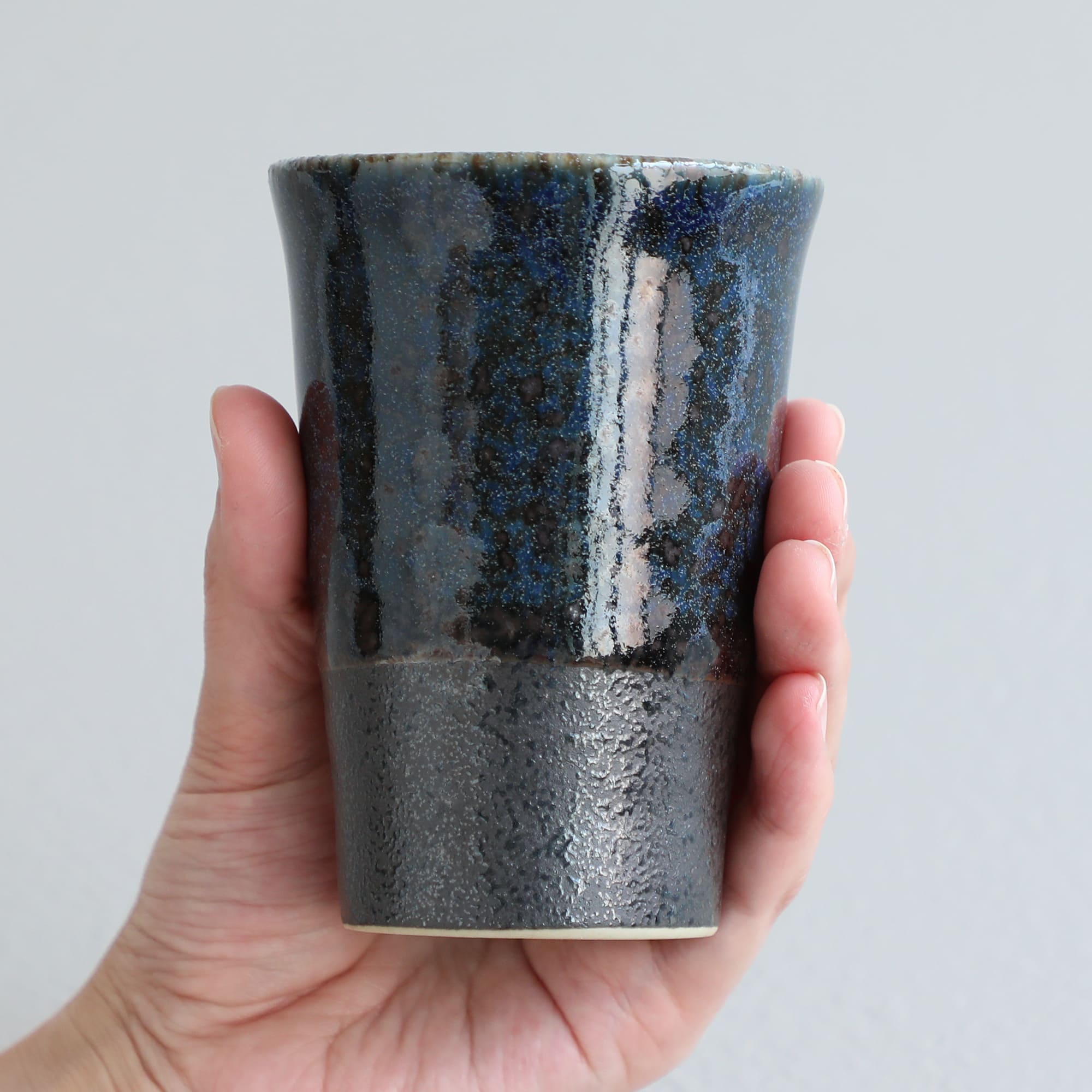 hand holding a blue tea cup