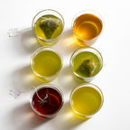 six glass with green tea including some tea bags