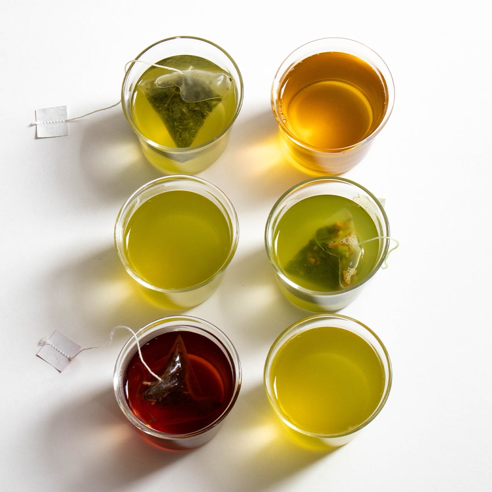 six glass with green tea including some tea bags