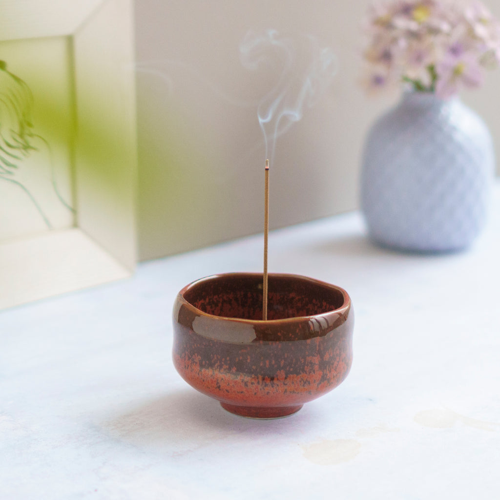 incense burning in an orange ceramic incense holder