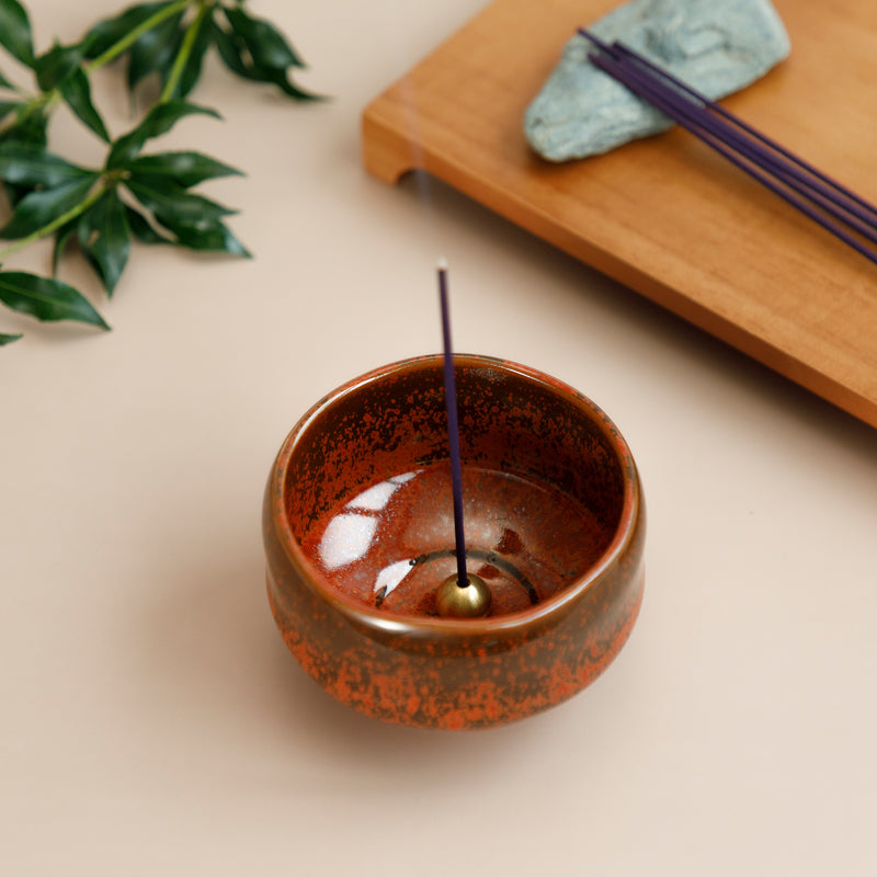 incense stick bunring in an orange incense holder