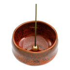 incense stick in orange ceramic holder with white background