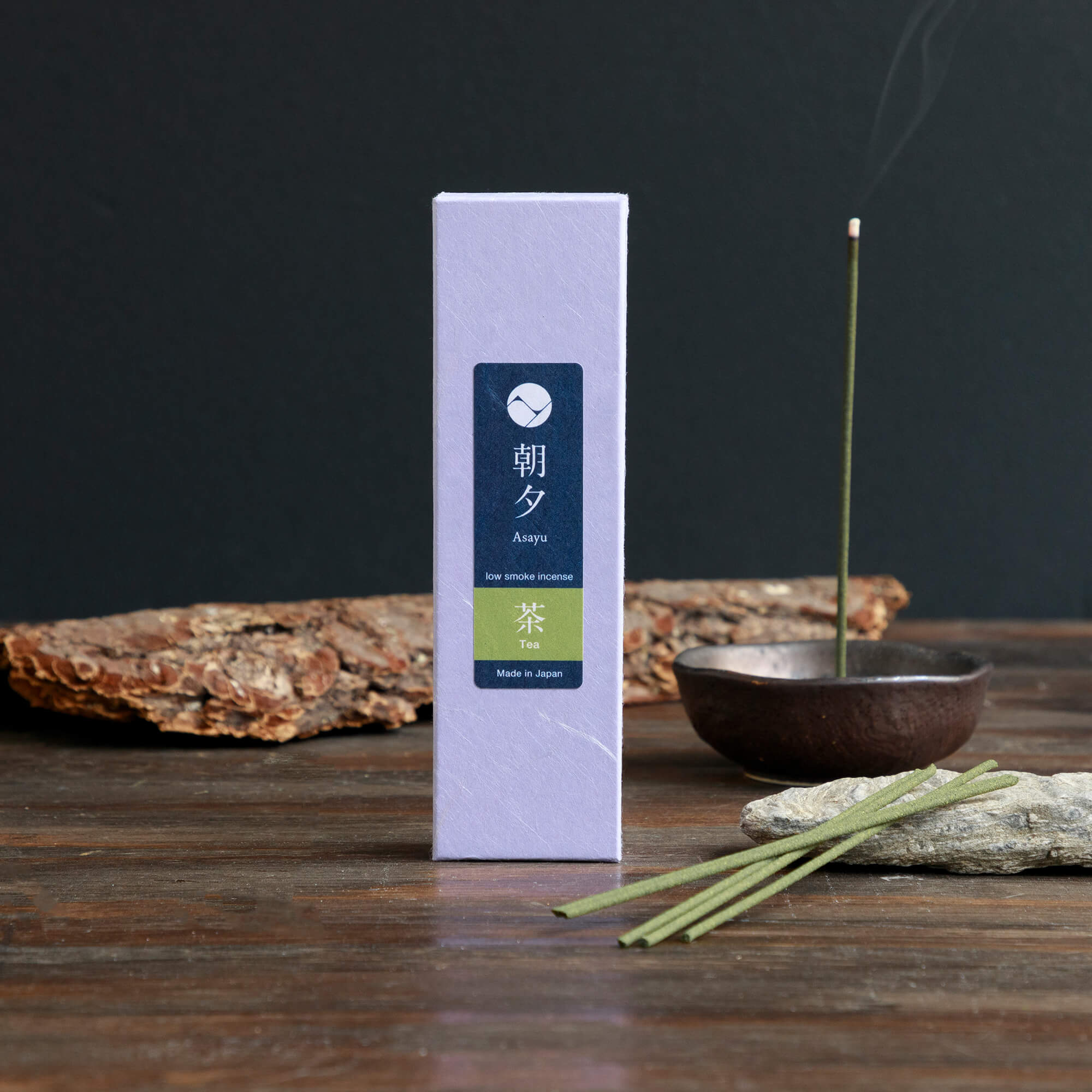 green tea incense with piece of wood bark next to incense holder