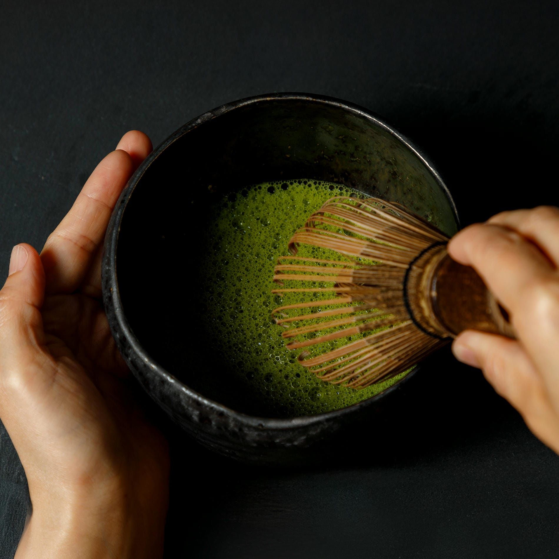 hand mixing matcha and hot water in a bowl