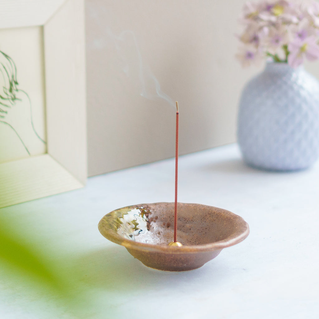 incense burning in brown ceramic holder