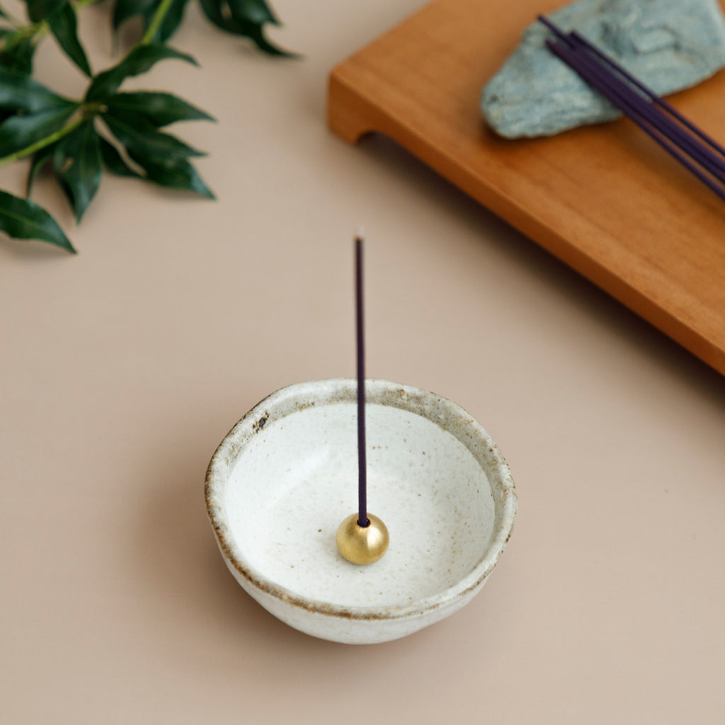 incense place in brass holder within white ceramic incense holder