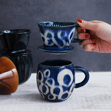 Cargar imagen en el visor de la galería, A hand holding the Asayu Japan Ceramic Coffee Dripper in Ocean blue over the matching accessory mug.
