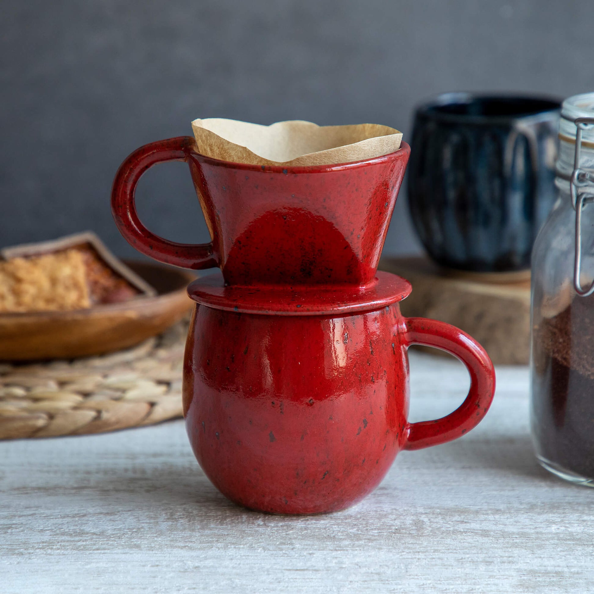 The Asayu Japan Coffee Dripper in chrome red put over the accessory mug and with a paper filter on it.