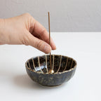 Put the incense stick in an incense stand over an incense plate or similar surface