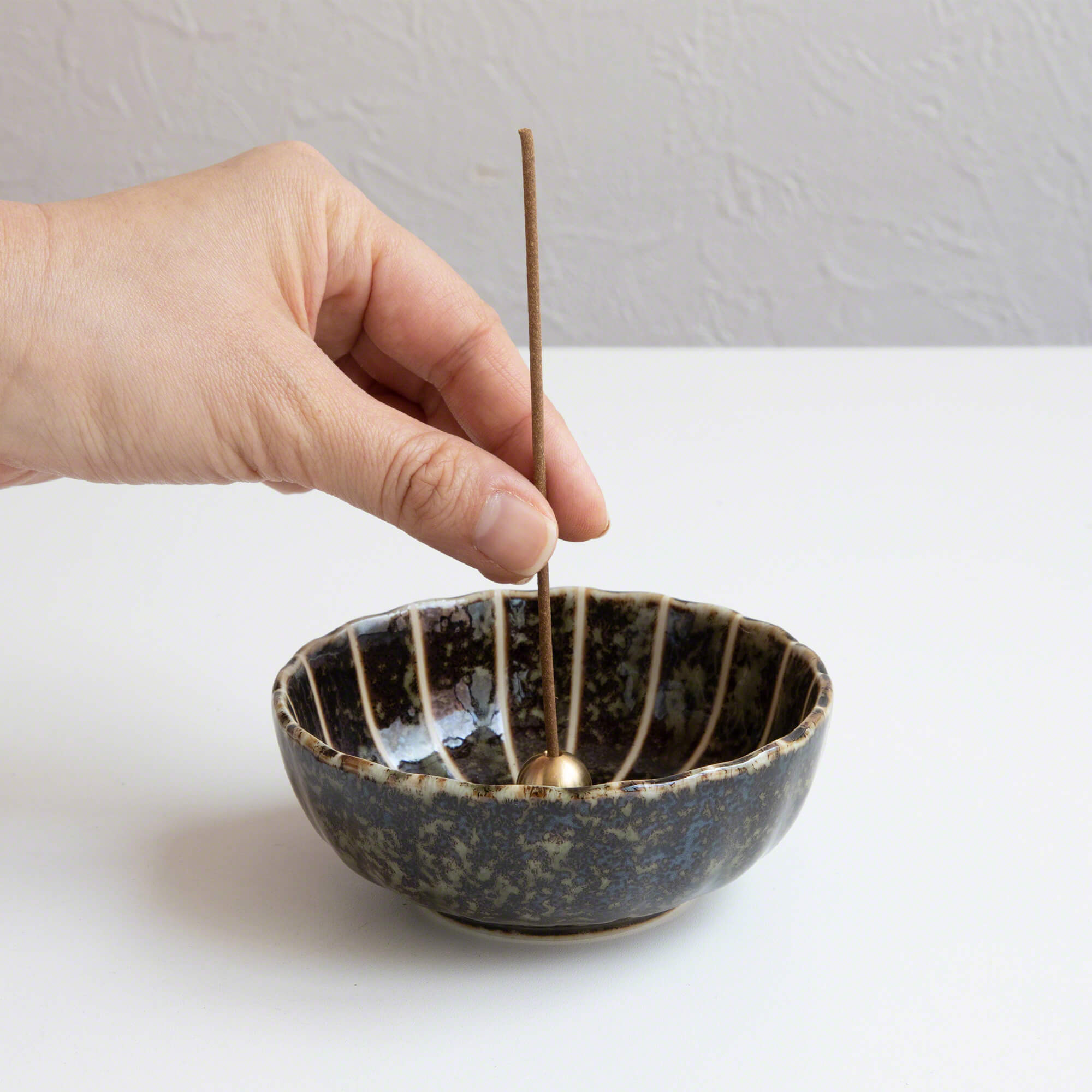 Put the incense stick in an incense stand over an incense plate or similar surface