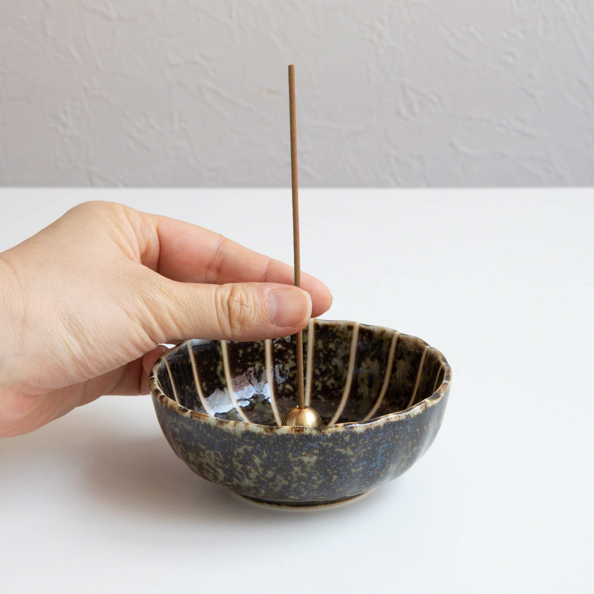 Put the incense stick in an incense stand over an incense plate or similar surface