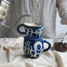 Cargar imagen en el visor de la galería, Pouring water over the paper filter on the mounted Asayu Japan Ceramic Coffee Dripper and Accessory Mug in ocean blue with white abstract pattern to make coffee
