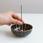 Put the incense stick in an incense stand over an incense plate or similar surface