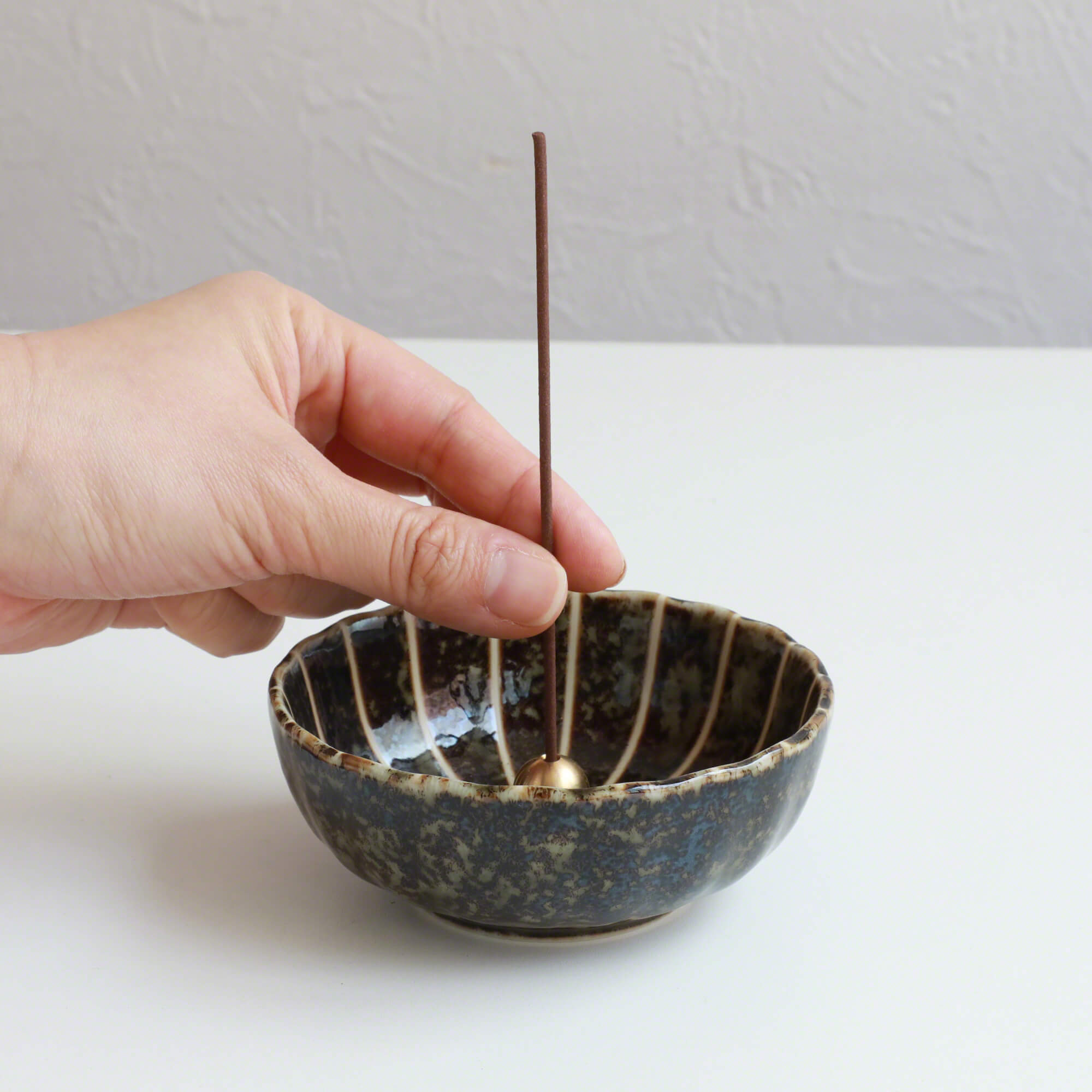 Put the incense stick in an incense stand over an incense plate or similar surface