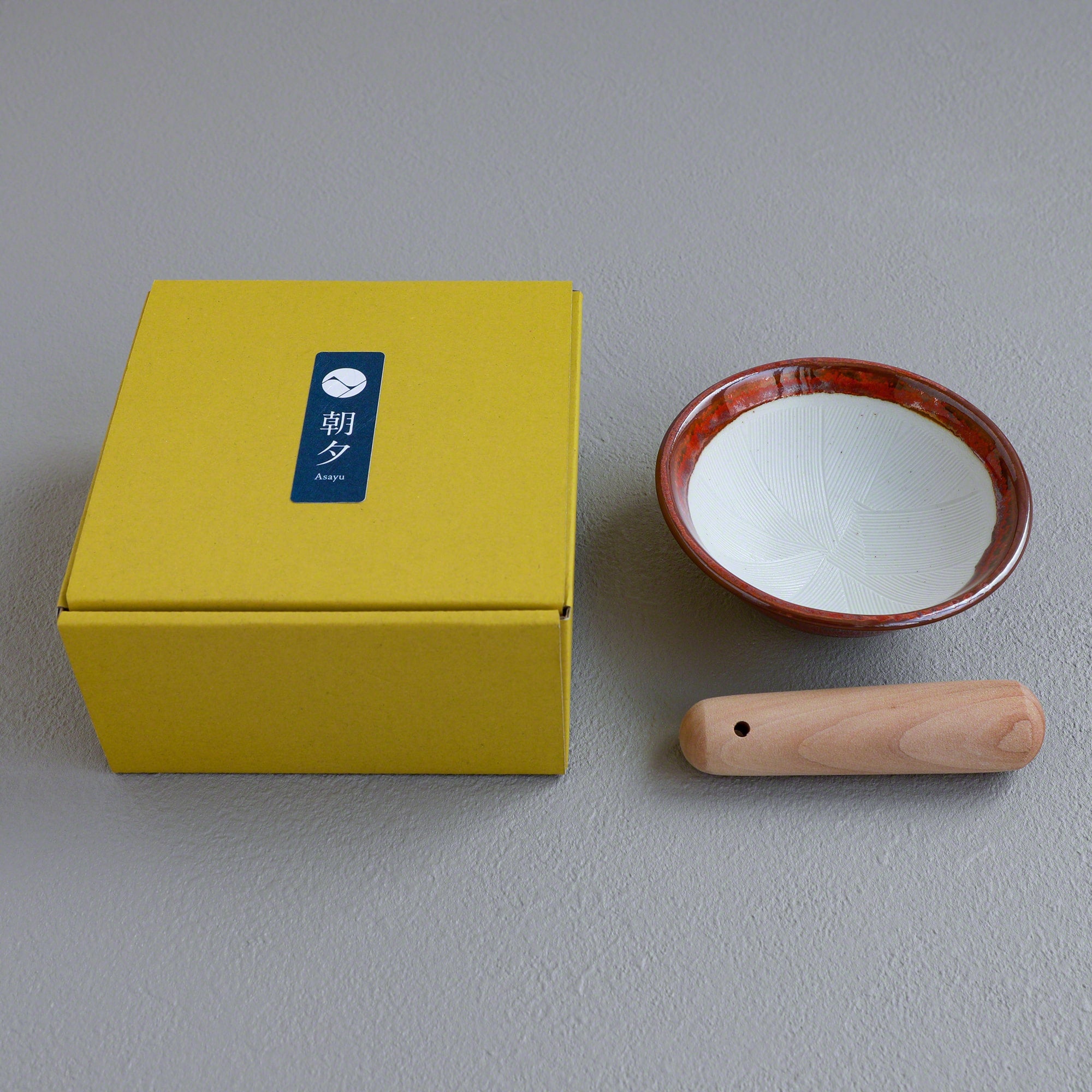 Picture of the Ceramic Red Mortar Bowl and Pestle Set with the packaging box with the Asayu Japan logo.