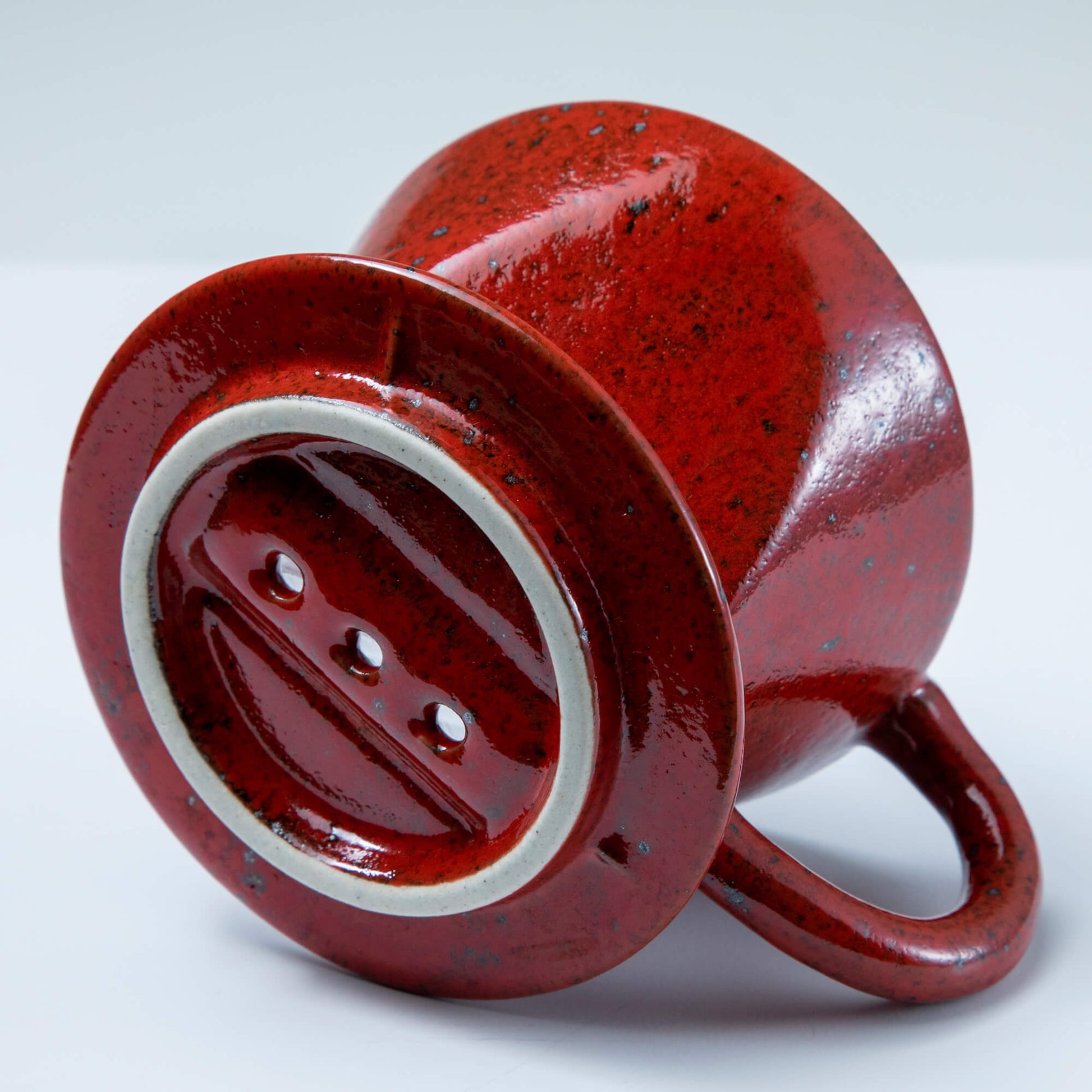 Bottom of the Asayu Japan Ceramic Coffee Dripper in chrome red with the 3 filter holes.