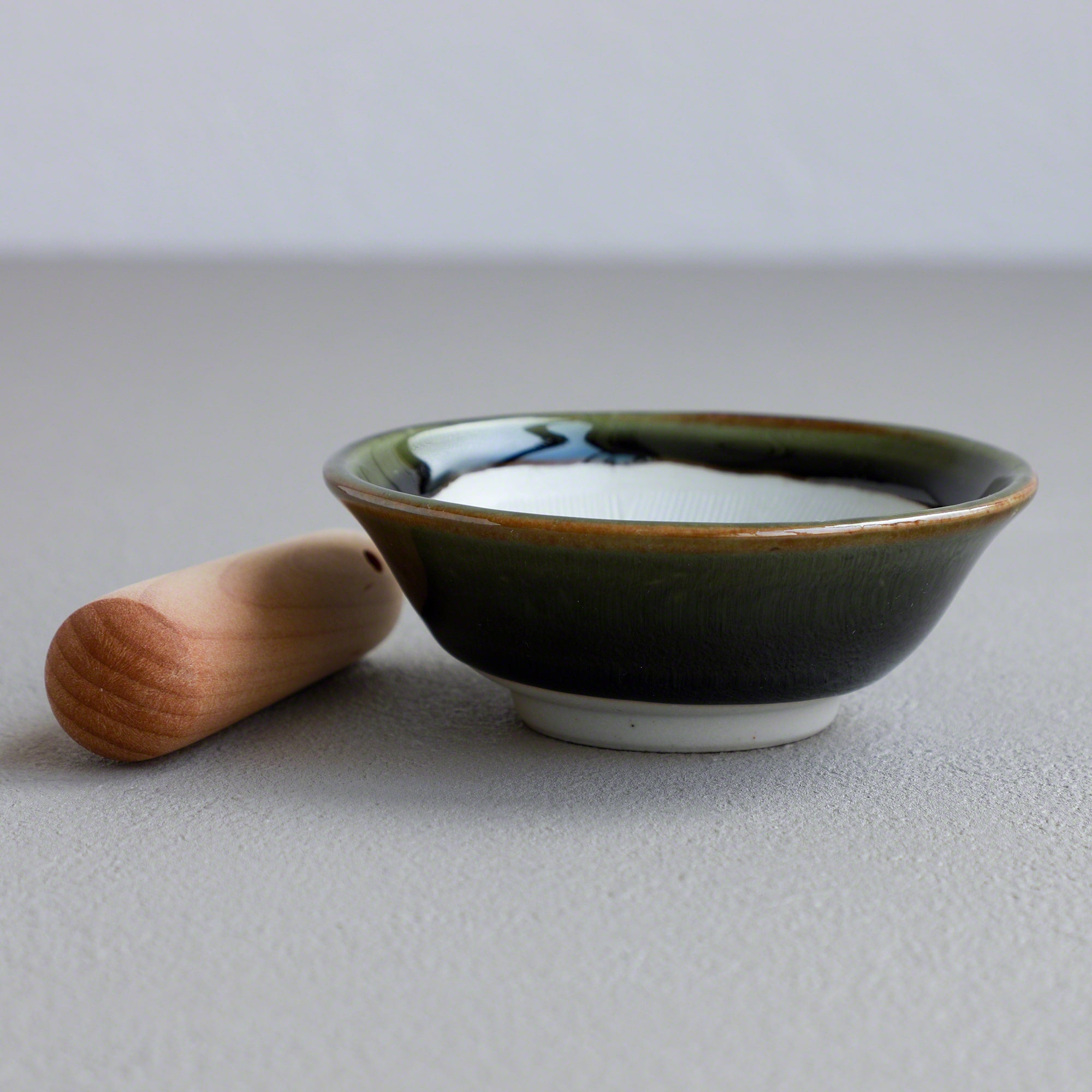 Asayu Japan Ceramic Olive Green Mortar Bowl and Wooden Pestle seen from the side.