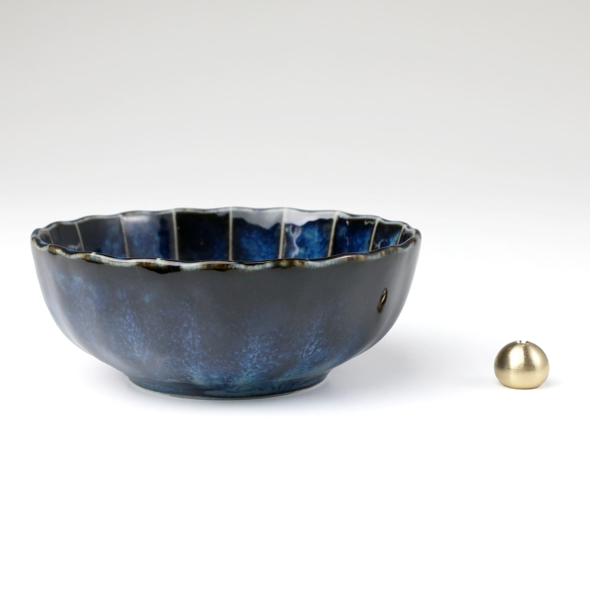 Asayu Japan dark navy blue lotus flower ceramic incense plate with included brass incense burner stand next to it from the side.